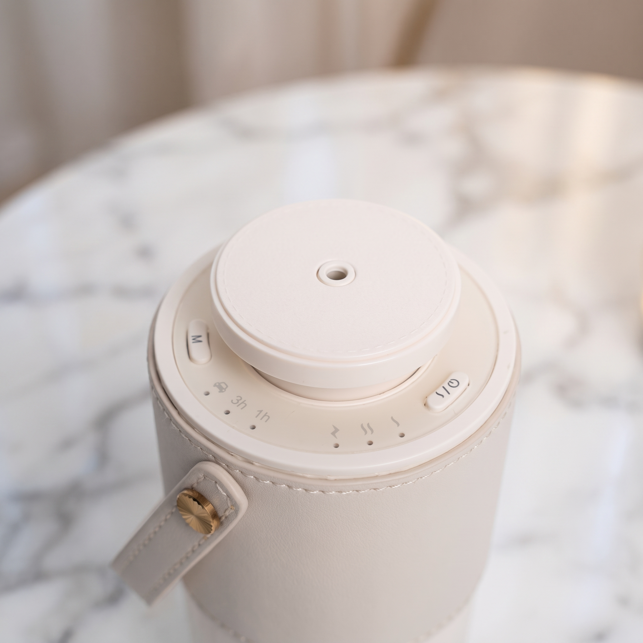 Close-up of the AURA Nomade controls: 1h and 3h timer, mist intensity and gold strap hardware