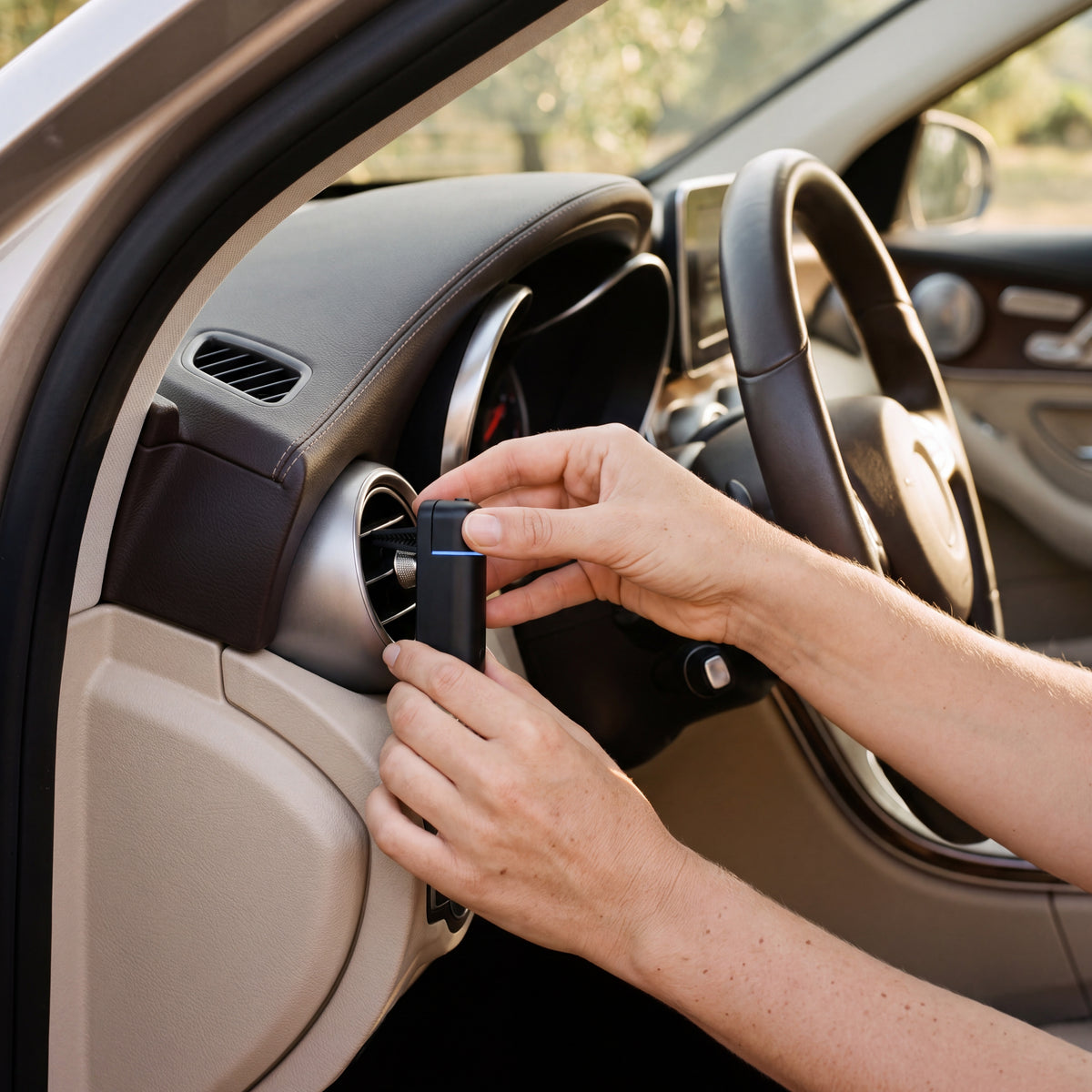 Hands clipping the black AURA Strada onto a round car air vent